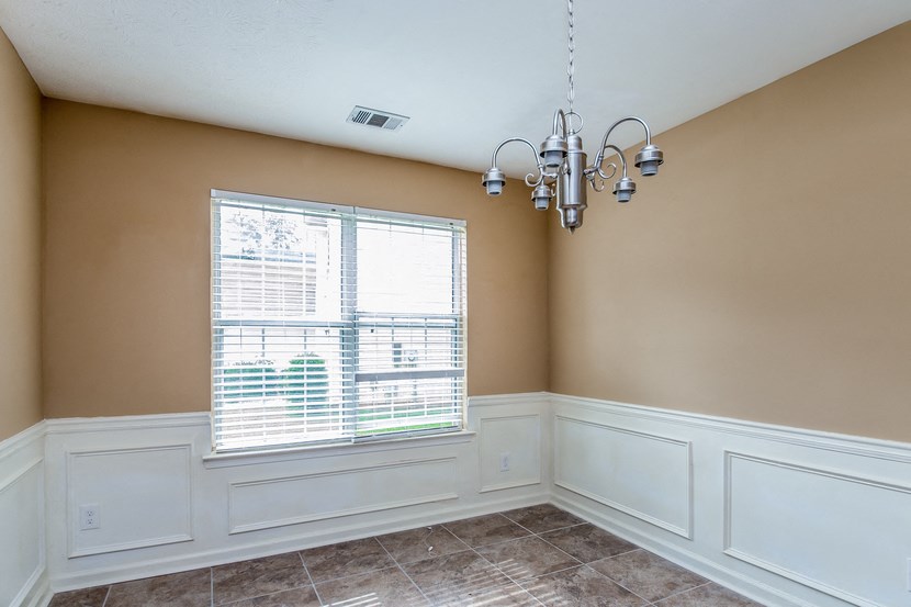 an empty dining room with a window and a chandelier