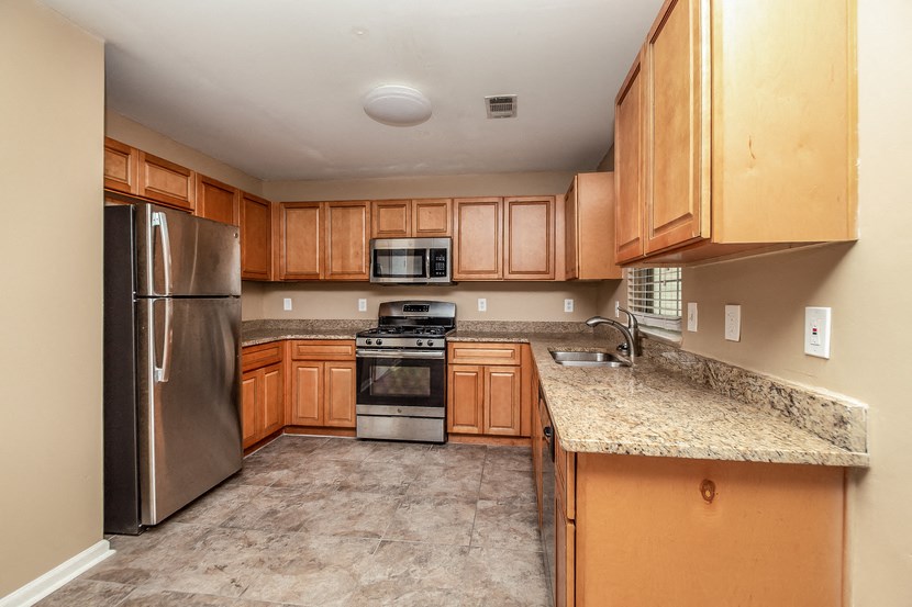 an empty kitchen with wooden cabinets and stainless steel appliances