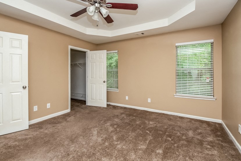 an empty living room with carpet and a ceiling fan
