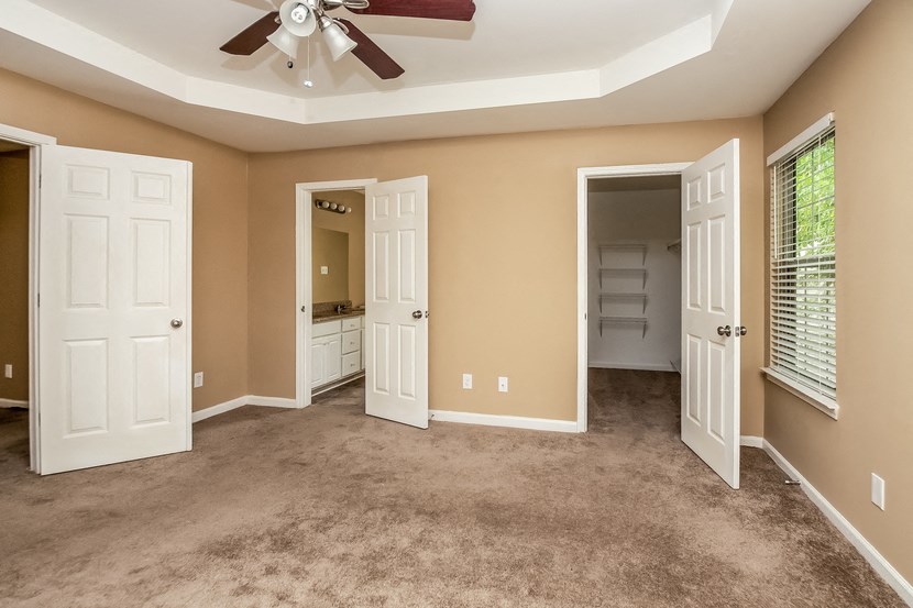 an empty living room with a ceiling fan and a closet