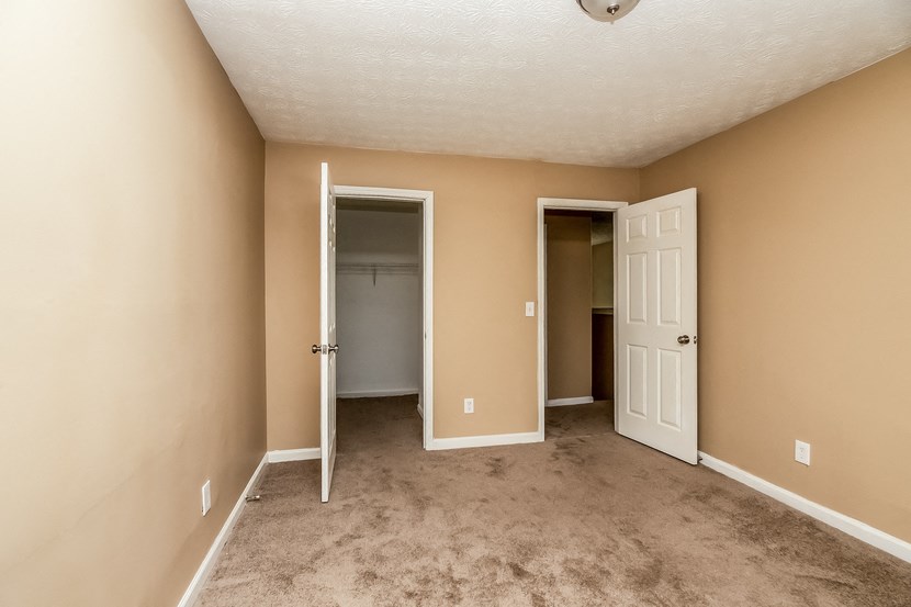 an empty room with a carpeted floor and a door to a closet