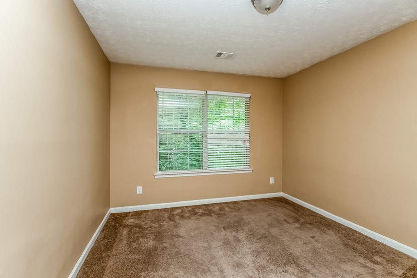 an empty bedroom with a large window and carpet