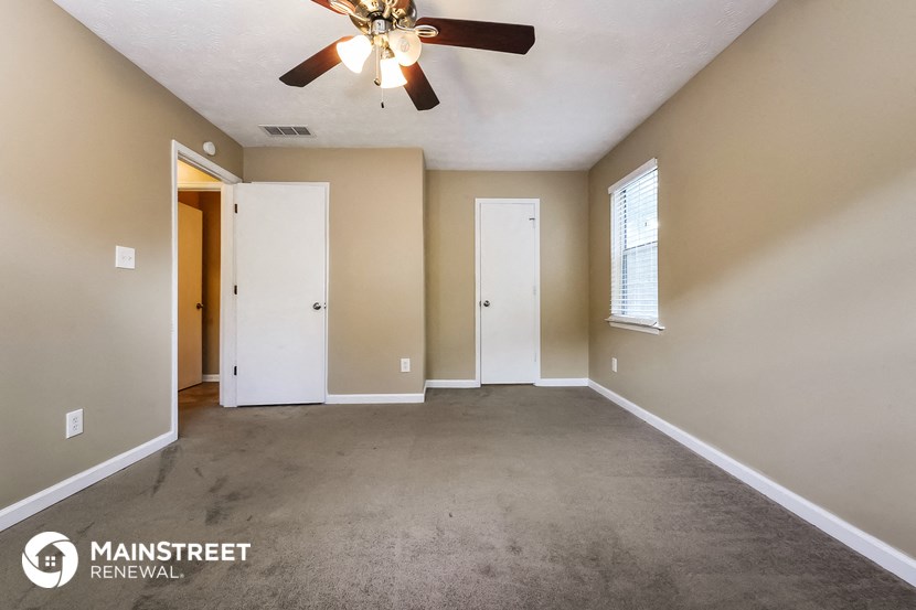 an empty living room with carpet and a ceiling fan