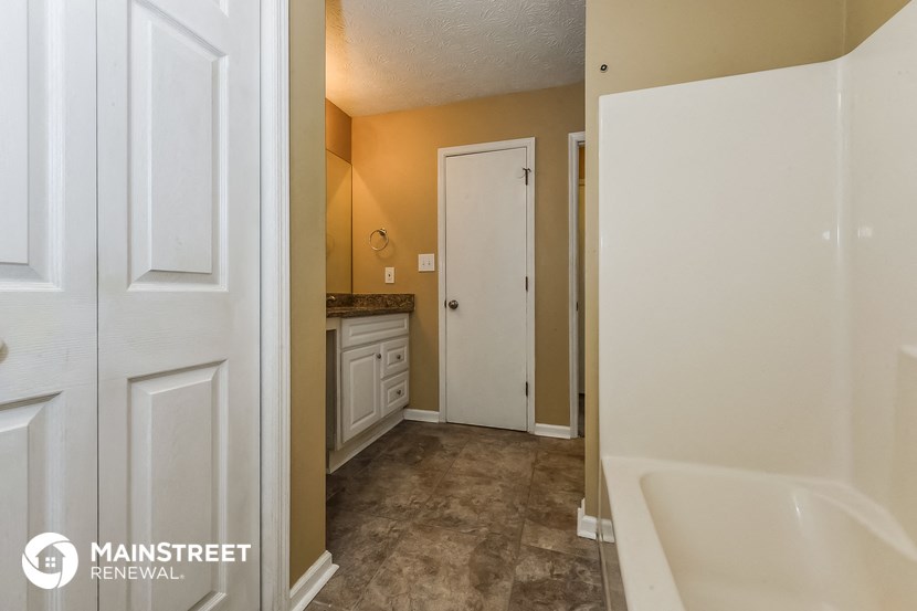 a bathroom with a tub and a sink and a door to a closet