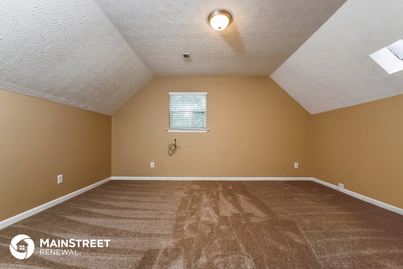the upstairs bedroom with carpeted flooring and a window