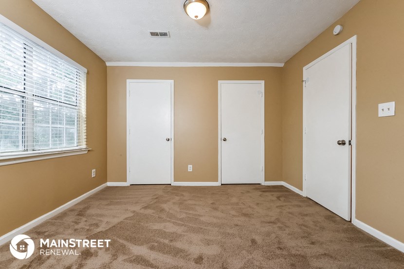 the living room of an apartment with a carpeted floor and two doors