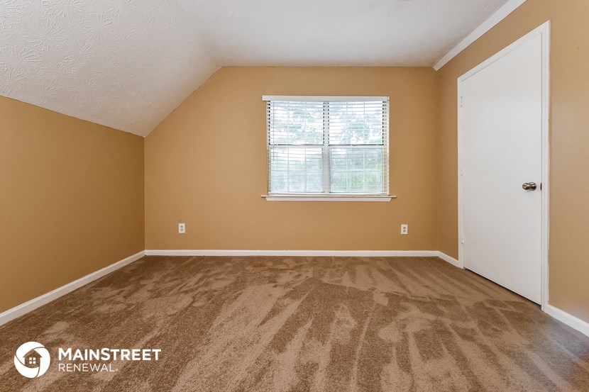 the upstairs bedroom with hardwood flooring and a window
