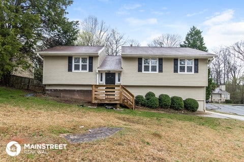 the front of a yellow house with a porch and a wood deck