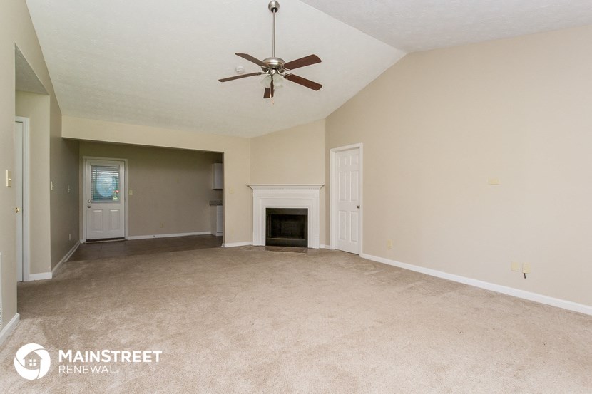 an empty living room with a fireplace and a ceiling fan