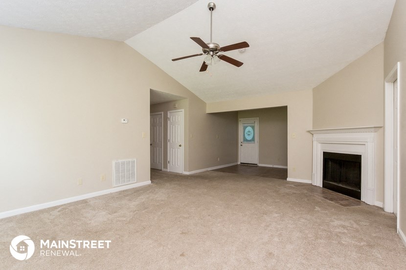 an empty living room with a fireplace and a ceiling fan
