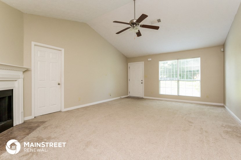 the living room of an empty house with a ceiling fan