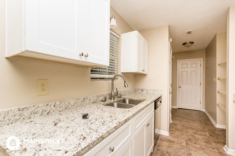 a kitchen with white cabinets and granite counter tops and a sink