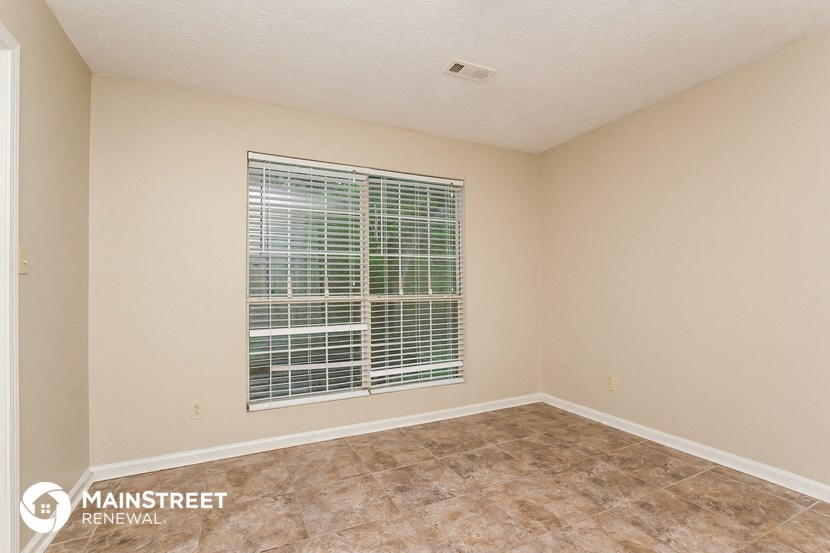 the spacious living room of a white house with a window