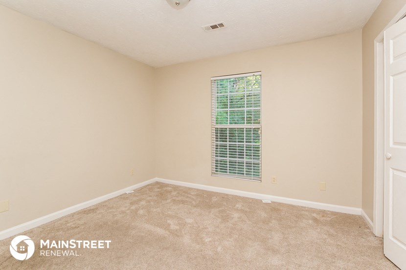 the spacious living room of this manufactured home has carpeting and a large window
