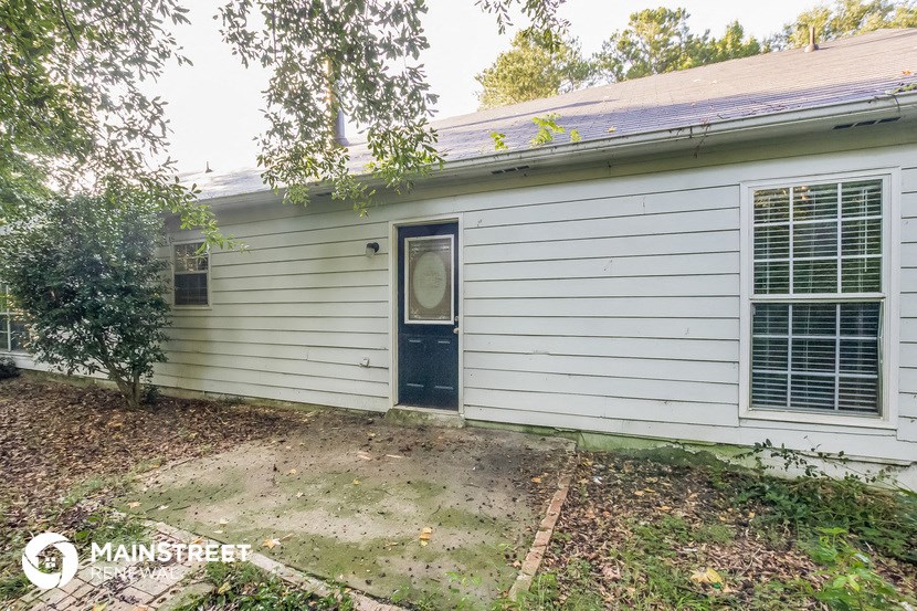the front of a white house with a black door