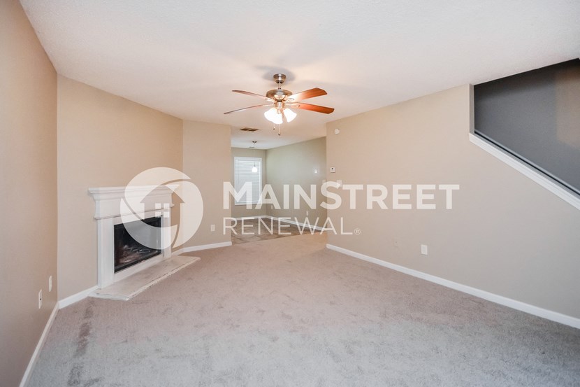 a living room with a fireplace and a ceiling fan