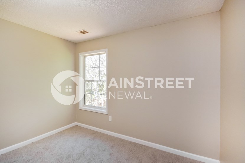 a bedroom with beige walls and a window