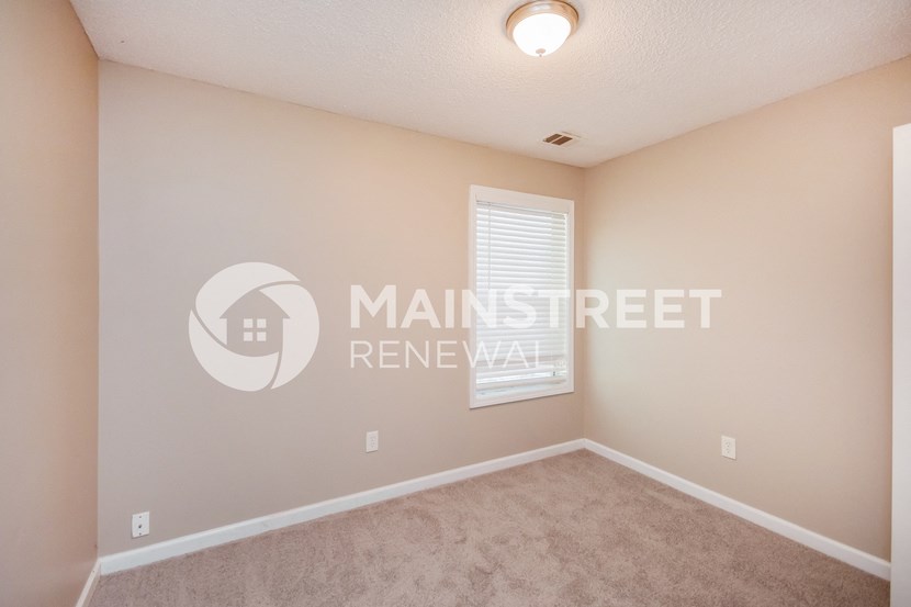 a bedroom with beige carpet and a window