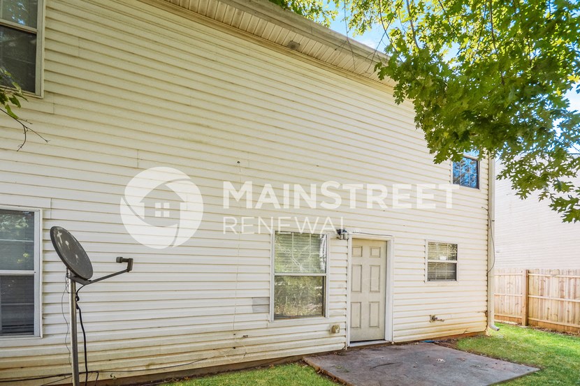 side of a white house with a yard and a mailbox
