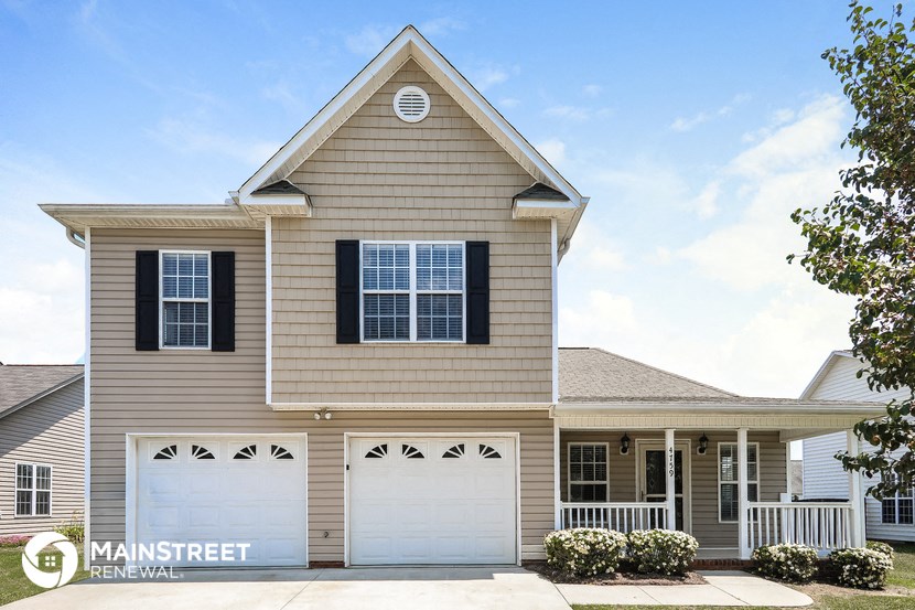 a tan house with two white garage doors