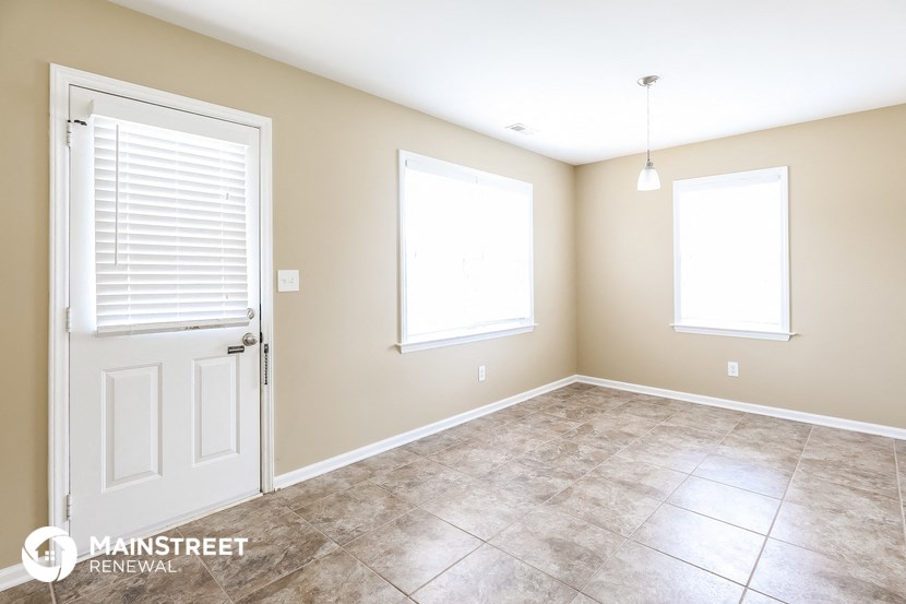 an empty room with a door and two windows