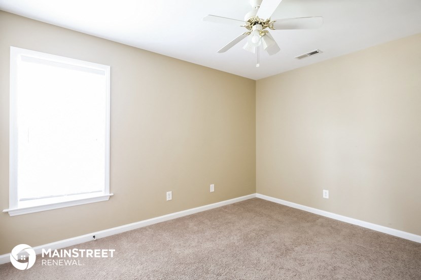 a carpeted room with a ceiling fan and a window