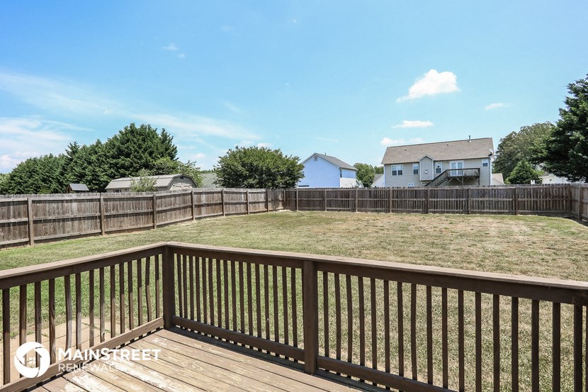 a backyard with a wooden deck and a fence