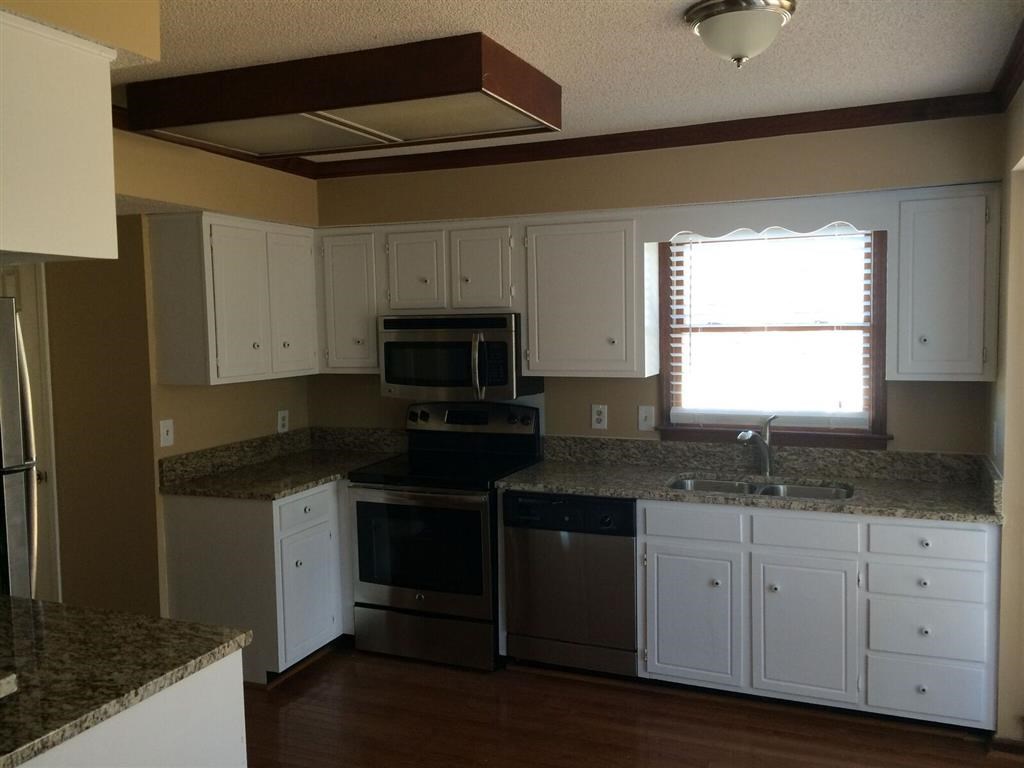 a kitchen with white cabinets and a stove and a window