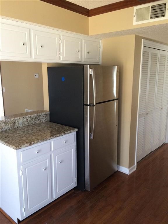 a kitchen with a stainless steel refrigerator and white cabinets