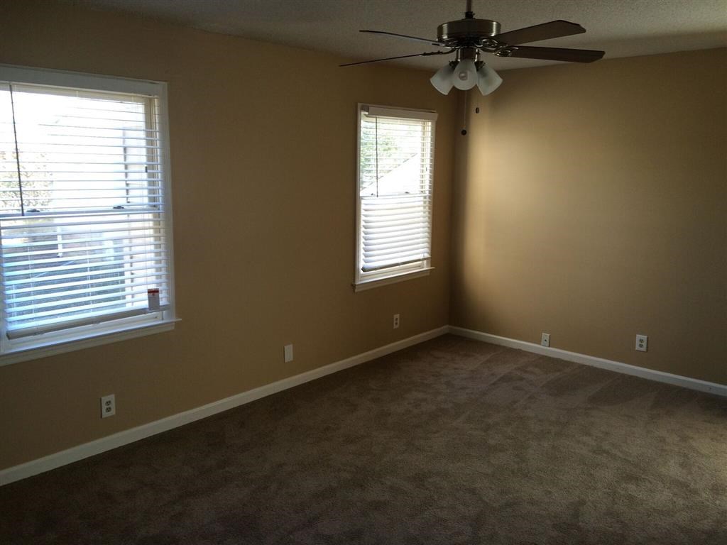 a empty room with a ceiling fan and two windows