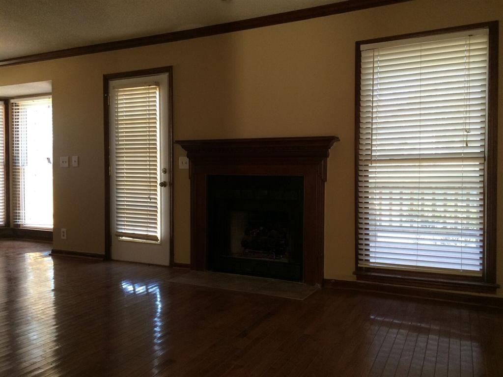 a living room with a fireplace and two windows with blinds