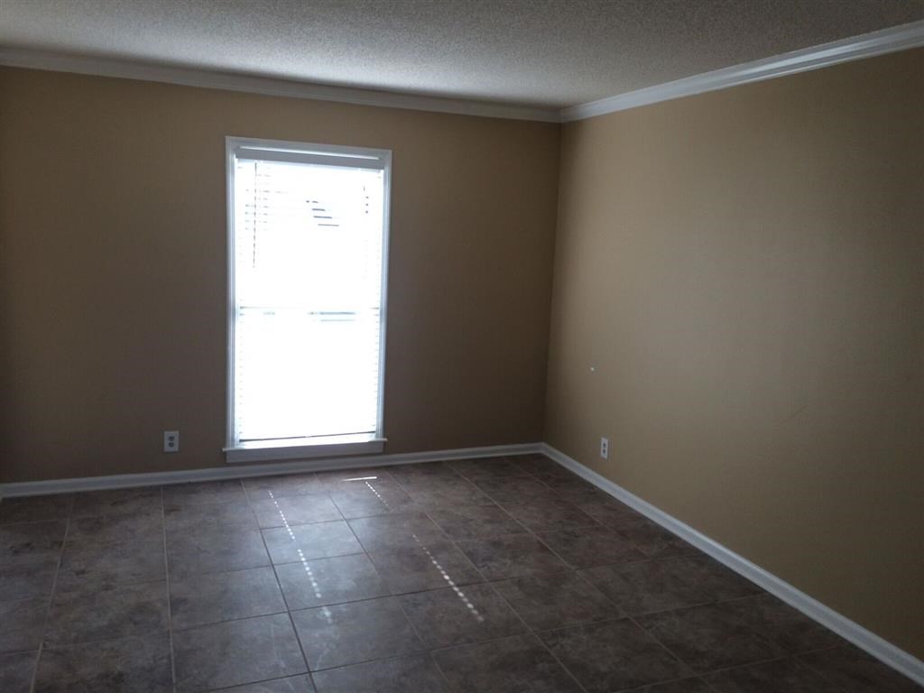 an empty living room with a window and tiled floors