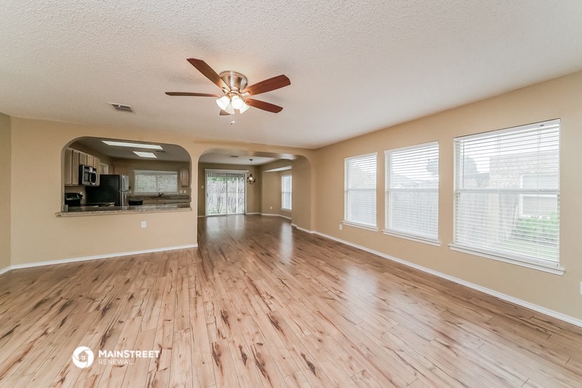 an empty living room with wood floors and a ceiling fan