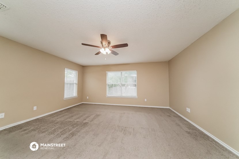 the spacious living room with carpet and a ceiling fan