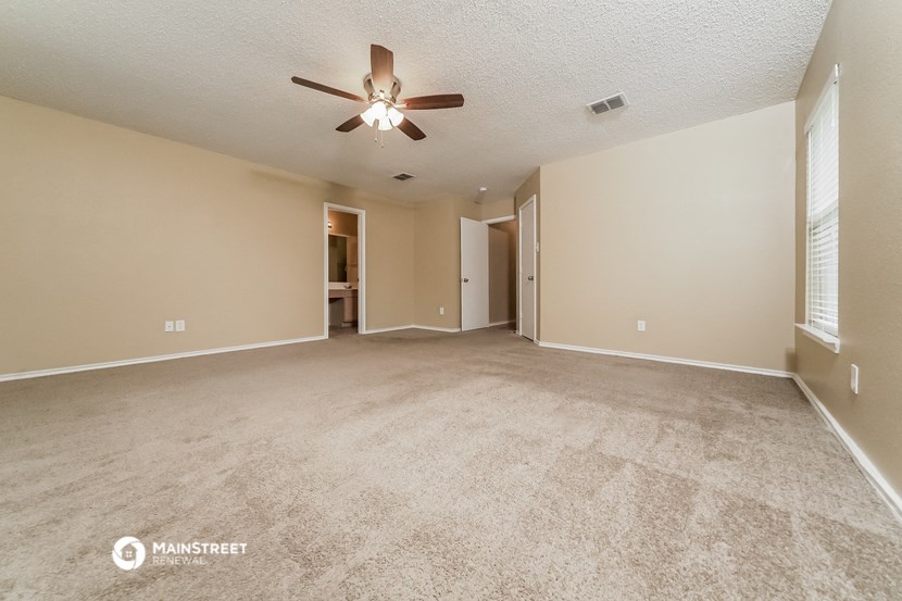 an empty living room with carpet and a ceiling fan
