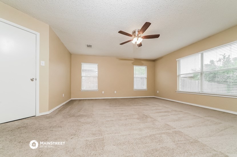 the spacious living room with ceiling fan and large window