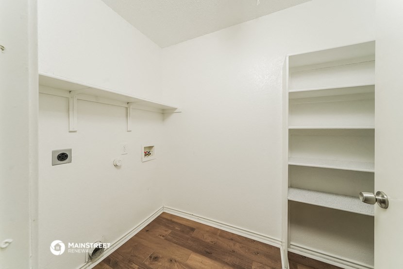 a bedroom with white walls and shelves and a wood floor