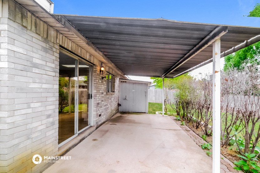a covered porch with a brick wall and glass doors