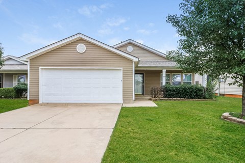 a beige house with a white garage door in front of a lawn