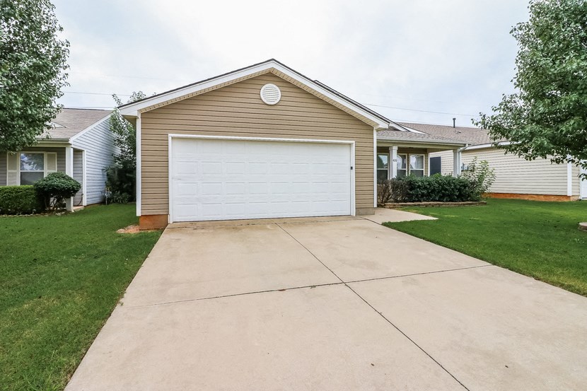 a white garage door on a tan house with a driveway