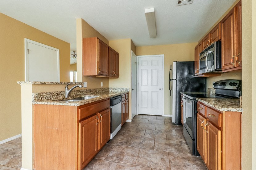 a kitchen with wooden cabinets and a black refrigerator