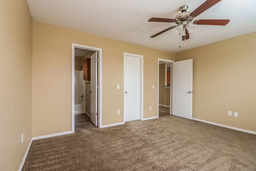 an empty living room with carpet and a ceiling fan