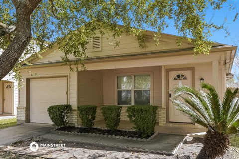 a small tan house with a white garage door