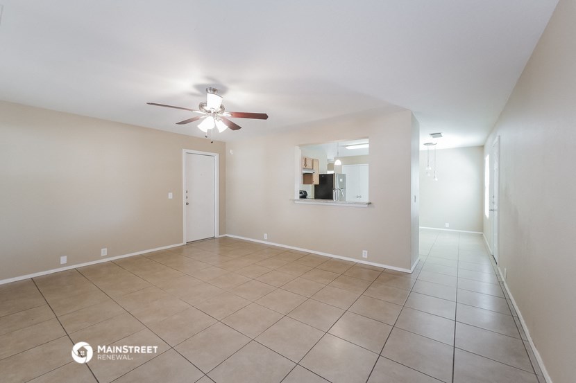 a spacious living room with tile flooring and a ceiling fan