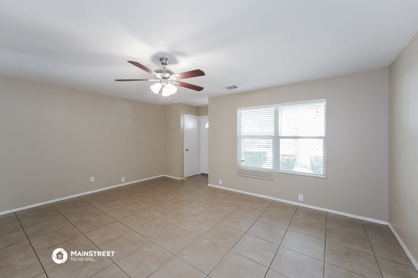 the spacious living room with ceiling fan and tiled floor