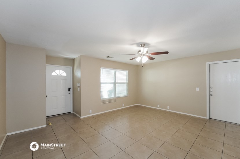 an empty living room with a ceiling fan and tiled floor