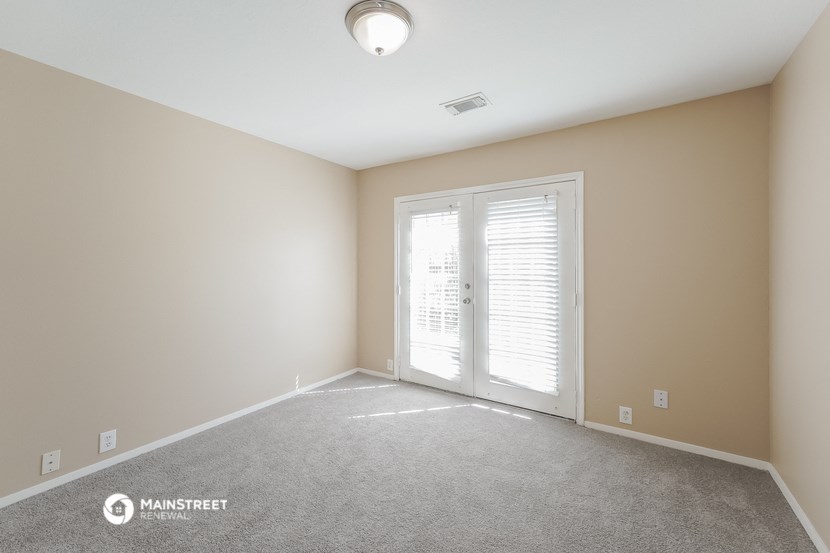the spacious living room of a new home with white carpet and a door to a