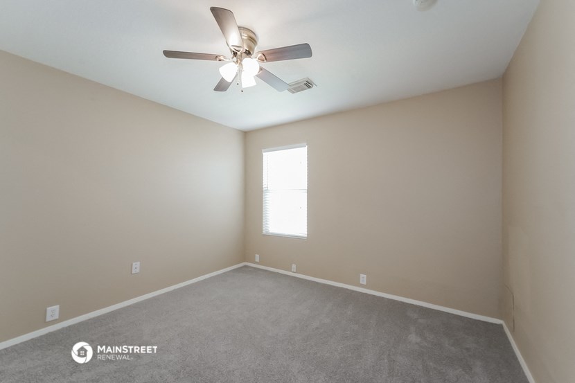 an empty room with a ceiling fan and a window