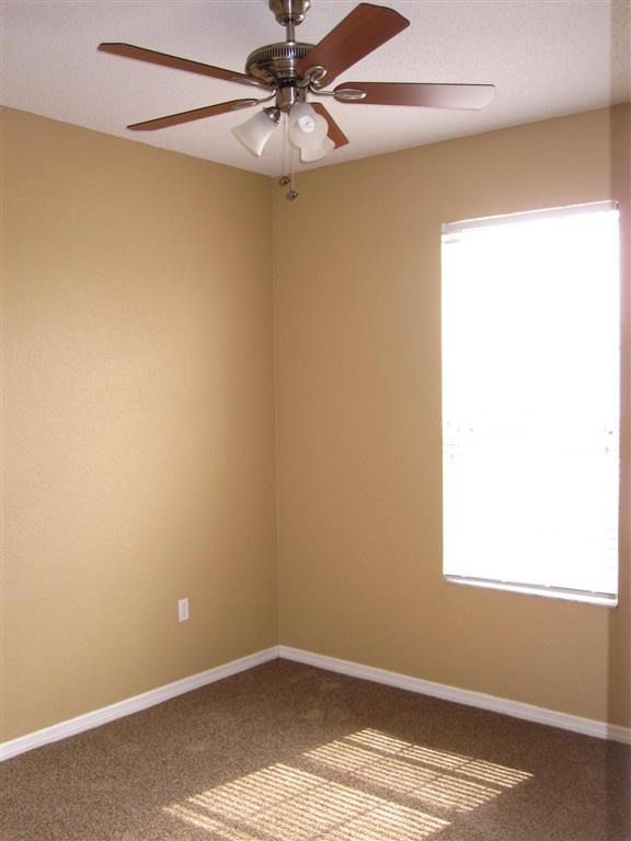 an empty room with a ceiling fan and a window