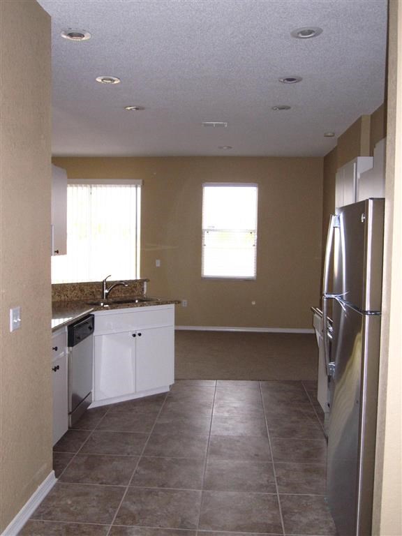 an empty kitchen with a refrigerator and a sink